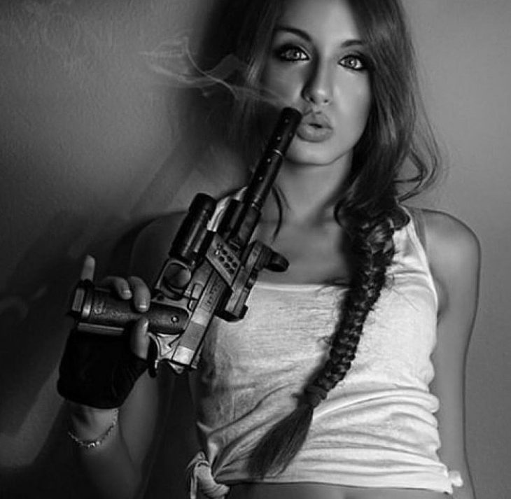 Фото злостной девушки с оружием в руках в маскировочной палатке